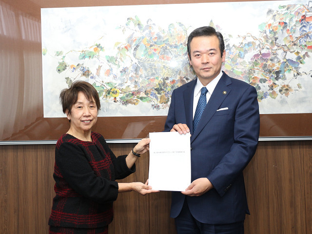 高橋淳子委員長から計画書を受け取る市長　