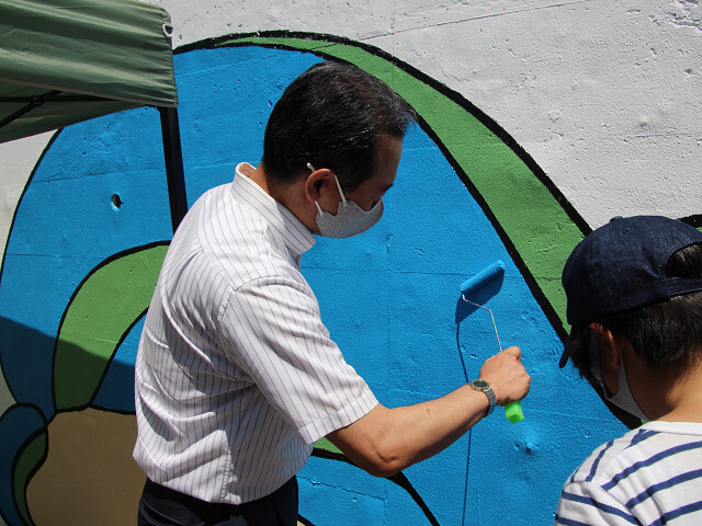 壁画塗装に参加する市長の写真